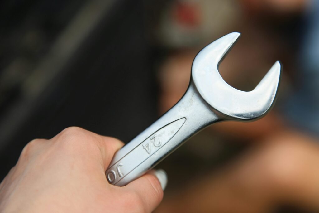 A hand holding a shiny metal wrench, ideal for repair and mechanic themed visuals.