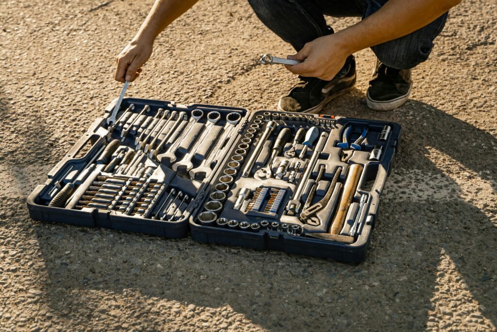 Mechanic organizing a toolkit outdoors on a sunny day, highlighting essential hand tools for repair and maintenance.